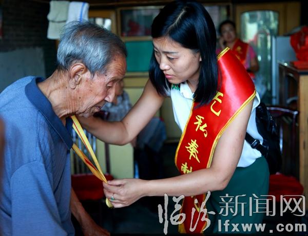 委員劉瑞玲幫郭生龍老人戴抗戰(zhàn)勝利70周年紀(jì)念章.jpg